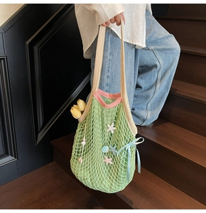 Detail of green woven mesh tote with starfish charms on a wooden staircase