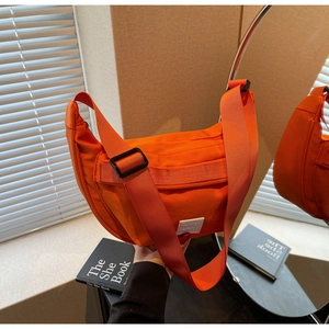 Détail du sac bandoulière demi-lune orange vif avec large sangle réglable en nylon