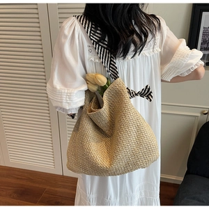 Dettaglio della grande borsa in paglia con tracolla a foulard a righe per le vacanze