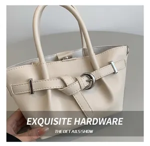 Gros plan sur la boucle en métal argenté et le cuir crème lisse du sac seau minimaliste