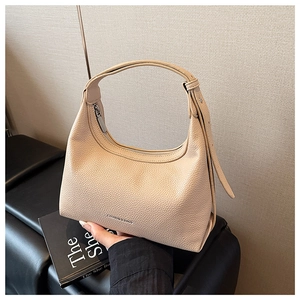Detail of beige lychee pattern leather hobo bag with adjustable strap on leather bench