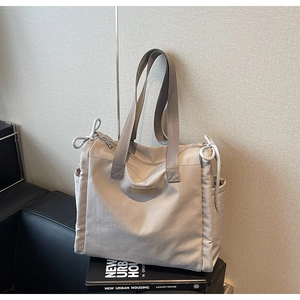 Dettaglio borsa tote in nylon beige con coulisse e tasche laterali su sedia di pelle