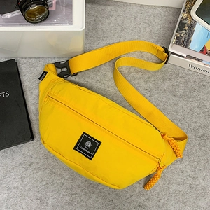 Top view of bright yellow nylon waist bag with accessories on a minimalist background