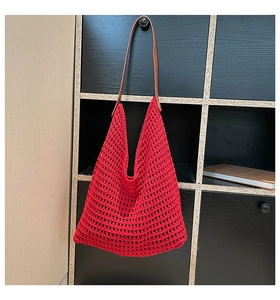 Detail of red hollow crochet tote bag featuring brown leather shoulder straps for beach