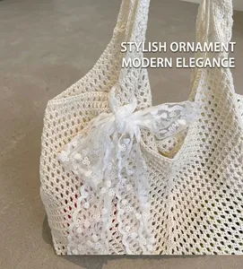 Détail du sac cabas en tricot crème avec tissage ajouré et décoration de nœud en dentelle