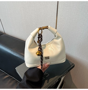 Dettaglio borsa in pelle cerata bianca con logo GOIN SDN e ciondolo intrecciato