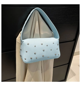 Detail of light blue pebble leather baguette bag featuring stylish silver rivet studs