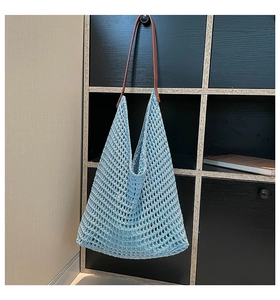 Detail of light blue hollow crochet tote bag with brown leather strap and metal rivets