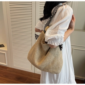 Dettaglio della borsa tote in paglia intrecciata con sciarpa decorativa a righe