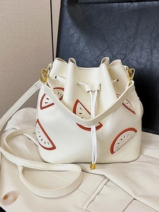 White bucket bag with orange cutout patterns and golden hardware on a stylish blazer