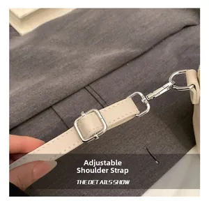Détail d'une bandoulière réglable en cuir crème avec boucle argentée et crochet