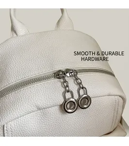 Detailed close-up of smooth silver circular metal zippers on white lychee leather backpack
