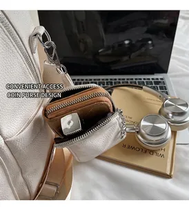Detail of white lychee leather coin purse attachment on a backpack with zipper closure