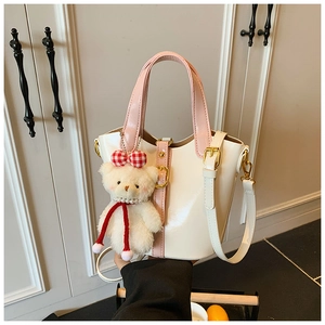 Detail van de roze en witte emmertas met een schattige pluche beer hanger en schouderband