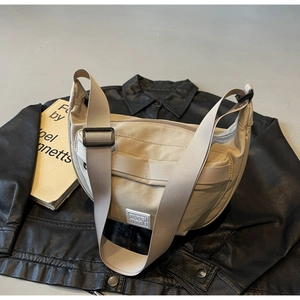 Détail du sac croissant en nylon beige avec bandoulière réglable sur veste en cuir