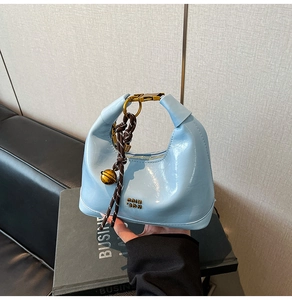 Dettaglio borsa in pelle azzurra cerata con campanello in ottone e manico intrecciato