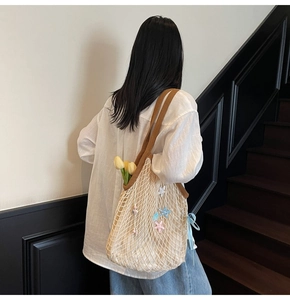 Close-up of beige mesh tote bag with blue ribbon and colorful star charm details