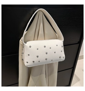 Macro shot of white lychee leather texture with silver dome rivets on a trendy bag