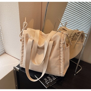 Dettaglio della borsa tote in nylon beige con coulisse laterale e toppa logo in pelle