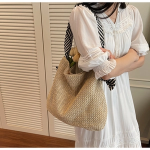Close-up of straw tote bag with black and white striped scarf handle and tulip decor