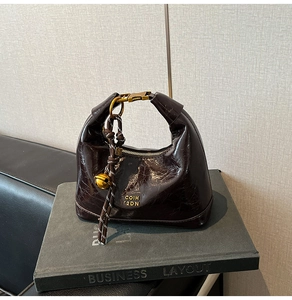 Dettaglio borsa in pelle cerata rosso scuro con chiusura dorata e trama craquelé