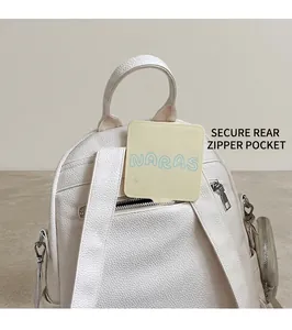 Close-up of a white leather backpack showing its anti-theft back zipper and straps