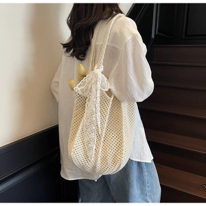Détail du sac tricoté blanc cassé avec nœud en dentelle et texture en maille ajourée
