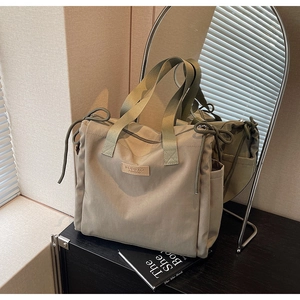 Dettaglio della borsa tote in nylon verde kaki con tasca laterale e marchio in pelle