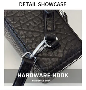 Close-up of black lychee grain leather bag with silver metal swivel hook and zipper detail