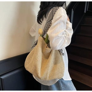 Dettaglio della grande borsa tote in paglia con sciarpa a righe e trama intrecciata naturale