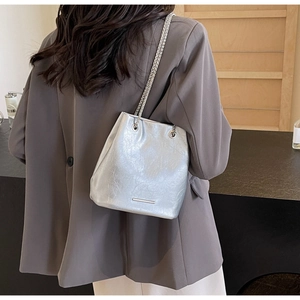 Detail of silver bucket bag with pleated shiny leather and elegant metal chain strap