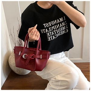 Détail du sac cabas bordeaux avec texture en cuir et boucle décorative à la main
