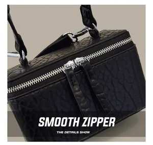 Detailed macro view of the textured black leather crossbody bag and smooth silver dual zippers