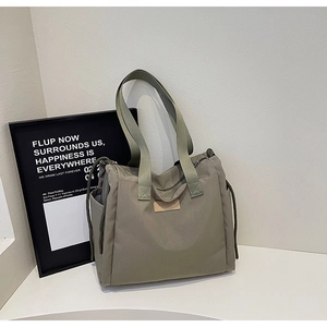 Dettaglio della borsa tote in nylon verde oliva con logo in pelle e tasca con coulisse