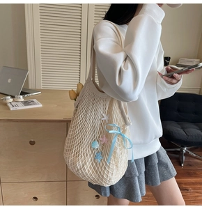 Close-up of beige crochet tote bag with blue ribbon bow and shell star charms