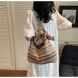 Dettaglio della borsa tote in paglia a righe colorate con tracolla e decorazione di tulipano
