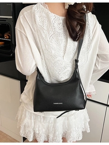 Minimalist black pebble leather hobo shoulder bag with thin strap in lifestyle setting