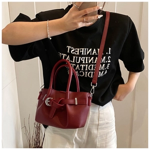Gros plan du sac seau bordeaux avec boucle en anneau argenté et bandoulière réglable