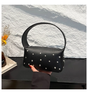 Close-up of black lychee texture leather handbag with silver stud accents and handle