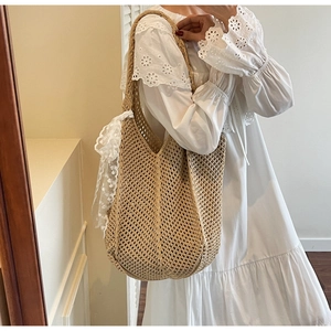 Gros plan sur un sac cabas en paille tressée avec écharpe en dentelle sur un mannequin