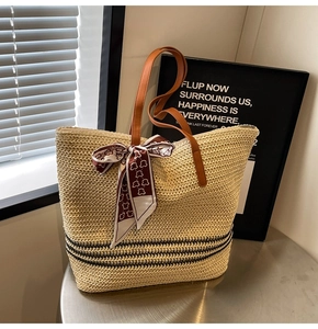 Detail of woven straw tote bag with black stripes and decorative silk scarf accessory