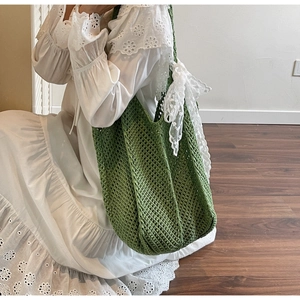 Détail d'un sac cabas en crochet vert avec motif tricoté et nœud décoratif en dentelle