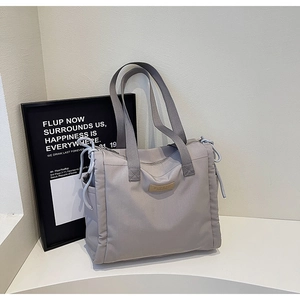Dettaglio della borsa tote in nylon grigio chiaro con coulisse laterali e logo in pelle