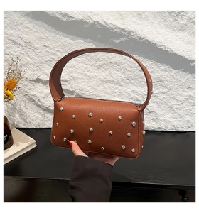 Detailed macro view of the brown lychee grain leather and silver stud accents on the handbag