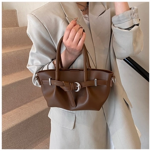 Détail du sac seau marron café avec boucle fer à cheval porté par un mannequin stylé