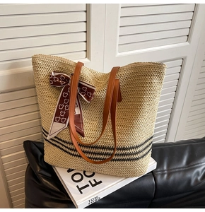 Detail of straw tote bag with black stripes, leather handles and decorative silk scarf