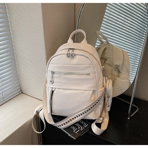Detail of white lychee leather backpack with printed wide straps and mini charm pouch