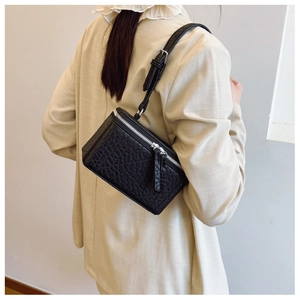 Detail of black pebbled leather mini crossbody bag with silver double metal zippers