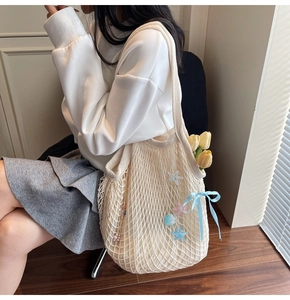 Close-up of beige crochet tote bag featuring marine star charms and light blue silk bow