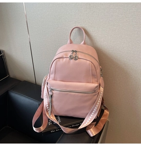 Detail view of pink PU leather backpack with arrow patterned straps on a black sofa